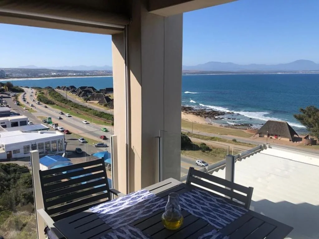 Expansive coastal view of blue ocean, beach, and mountains from deck
