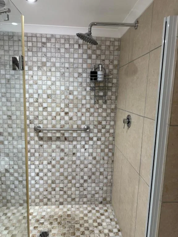 Modern shower enclosure with mosaic tile walls and rainfall showerhead