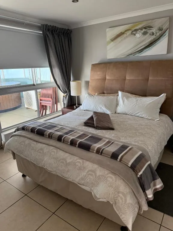Modern bedroom with brown upholstered headboard, ocean view through sliding doors