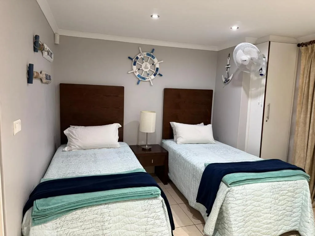 Twin bedroom with dark wood headboards, white bedding, nautical decor