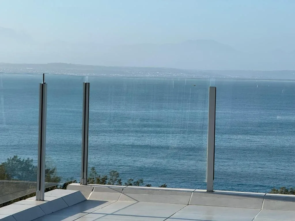 Modern balcony with glass railings overlooking Mossel Bay ocean and coastline