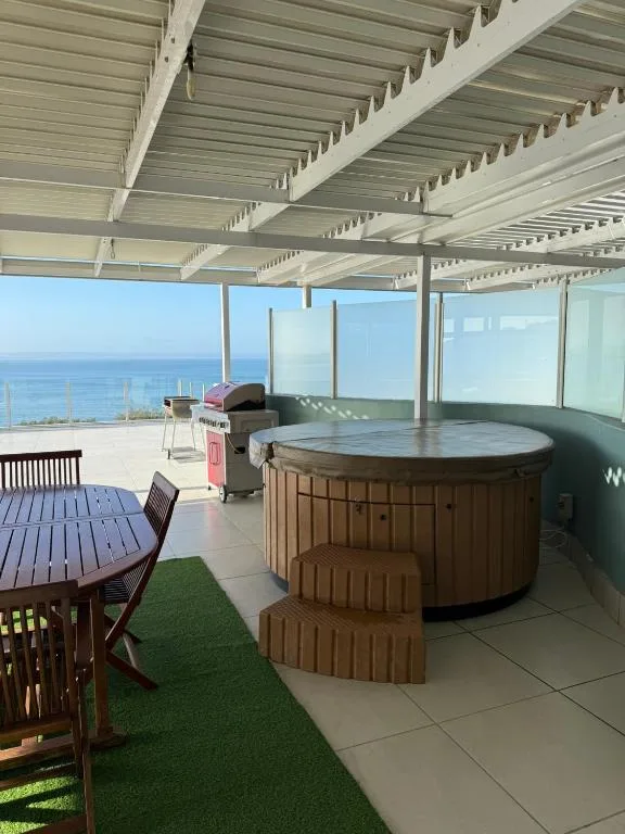 Covered ocean-view deck with hot tub, dining table, and braai area