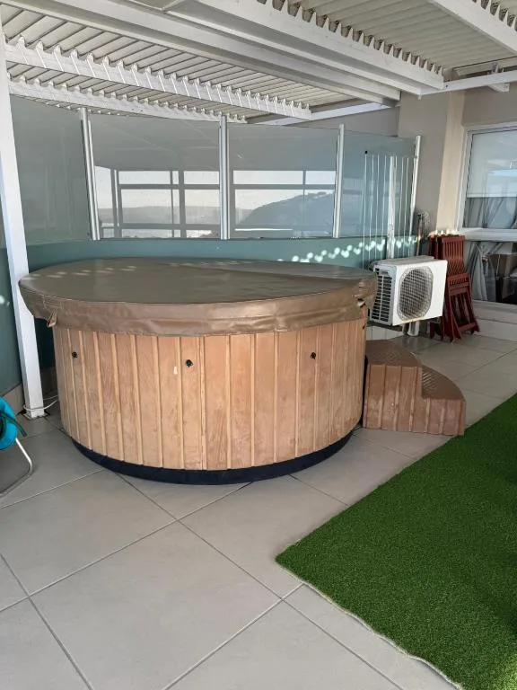 Wooden hot tub with cover and heating unit on covered deck