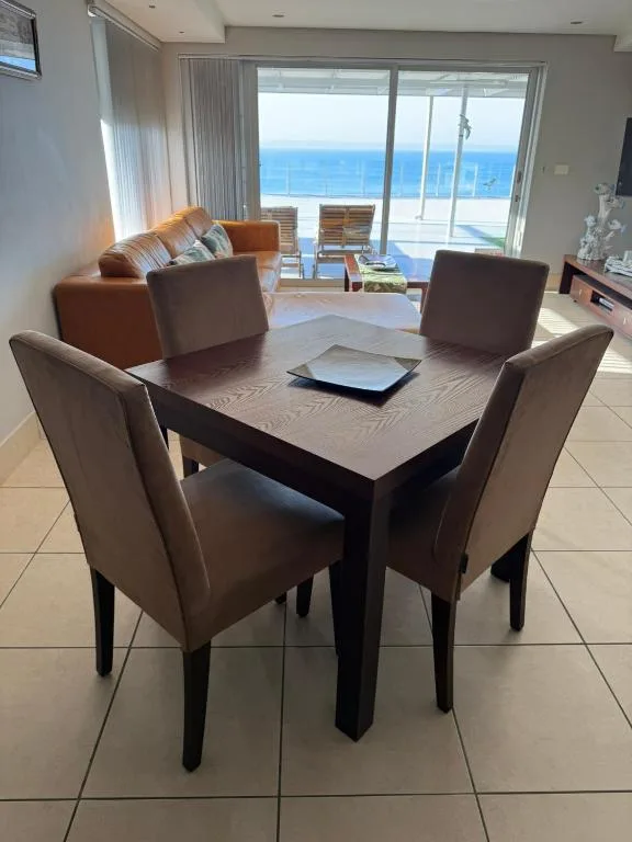Dining table with four chairs overlooking ocean views through large windows