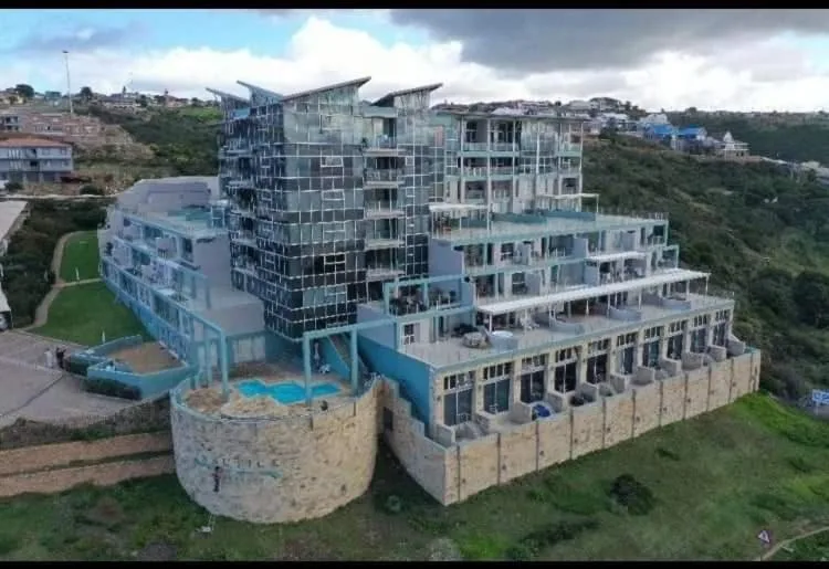 Modern multi-story beachfront apartment building with blue and white facade