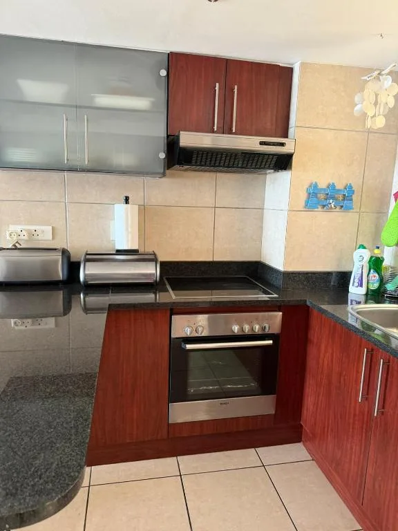 Modern kitchen with red cabinetry, stainless steel appliances, and dark countertop