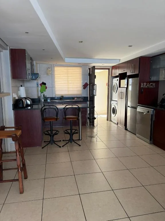 Modern kitchen with burgundy cabinetry, stainless steel appliances, and breakfast bar seating