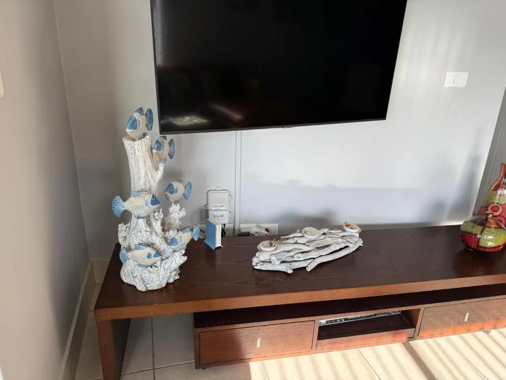 Wall-mounted TV above wooden entertainment unit with decorative fish sculpture