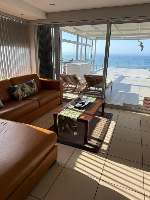 Modern lounge with brown leather sofa overlooking ocean views through glass doors
