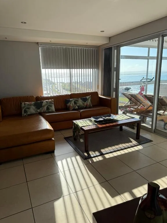Modern lounge with cognac leather sofa, coffee table, ocean views through large windows