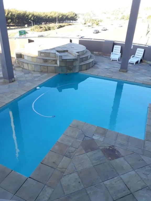 Bright blue swimming pool with surrounding paved deck and lounge chairs