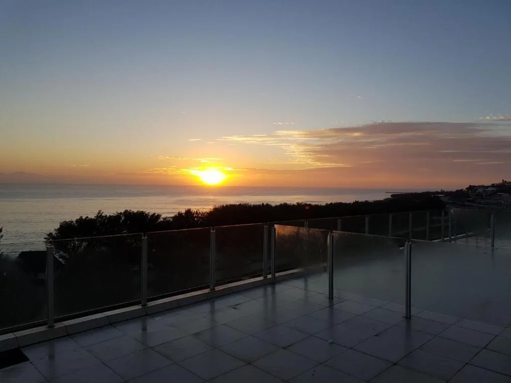 Sunset over ocean from elevated deck with metal railings