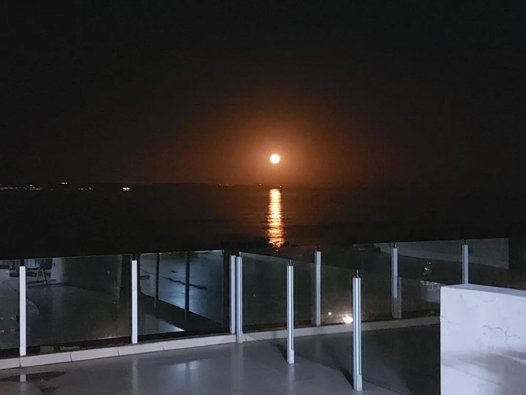 Full moon rising over calm lagoon waters at night from deck