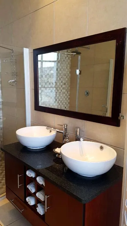 Modern bathroom with dual round white basins and dark stone countertop