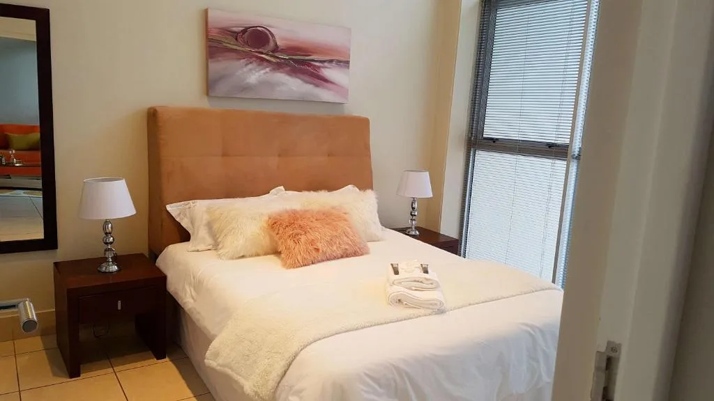 Bright bedroom with orange upholstered headboard and crisp white bedding