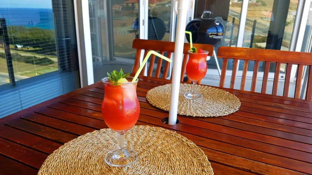 Wooden deck with ocean views, cocktails, braai grill, and coastal seating area