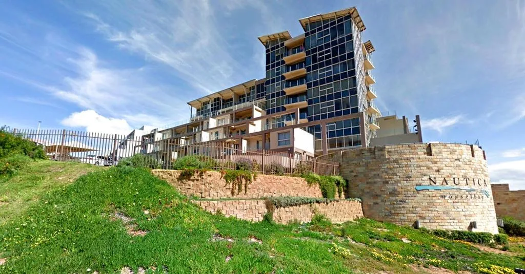 Modern beachfront apartment building with stone facade and green landscaping