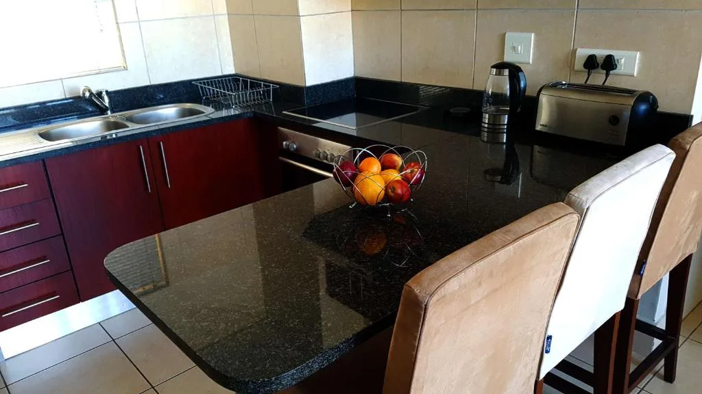 Modern kitchen with burgundy cabinetry, black countertop, and breakfast bar seating