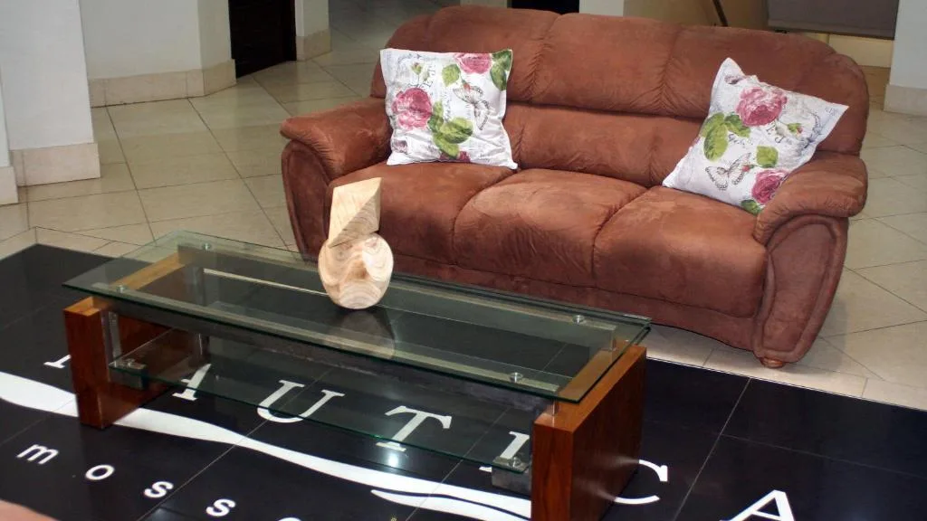 Spacious lounge with burgundy sofa, floral cushions, and glass coffee table