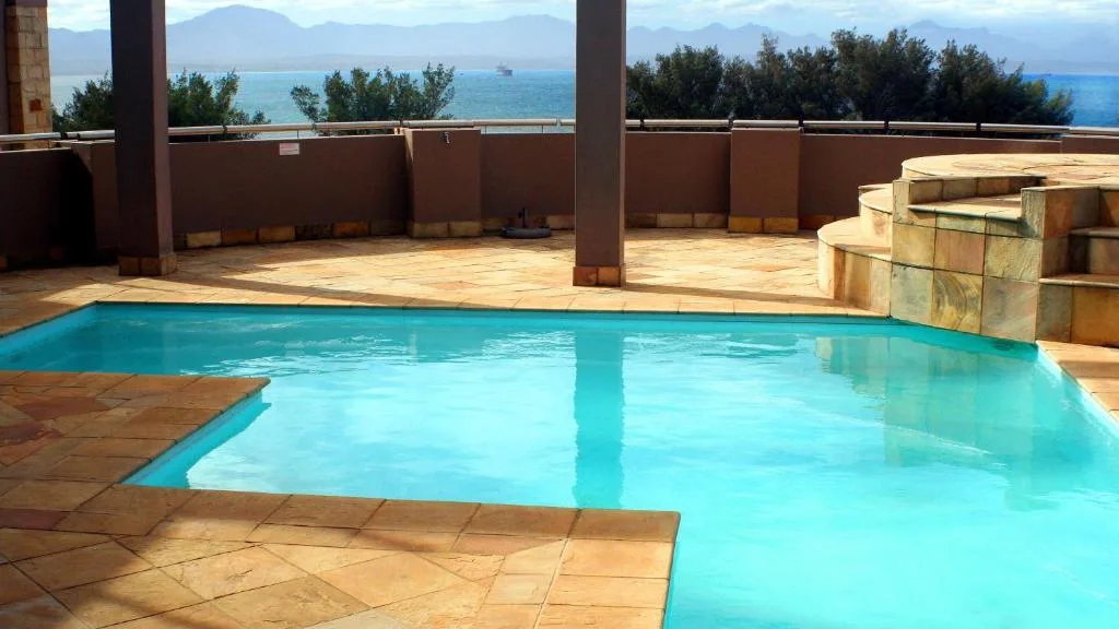 Sparkling turquoise swimming pool overlooking the ocean and mountains