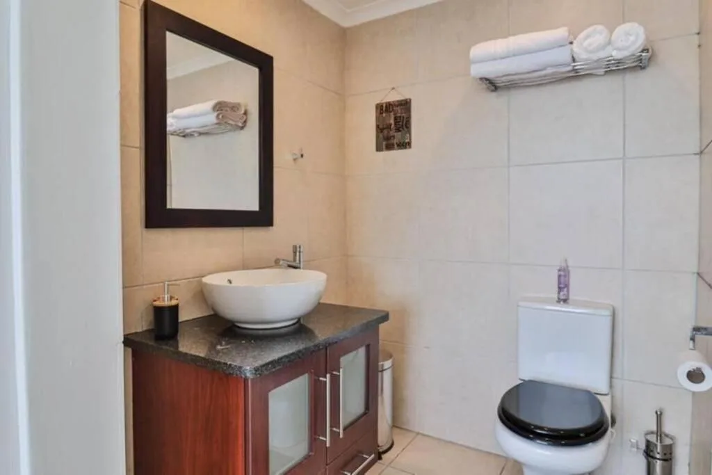 Modern bathroom with round vessel sink, dark vanity, framed mirror, and toilet