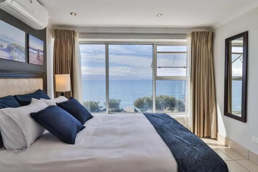 Spacious bedroom with ocean view through large windows and sea-facing balcony doors