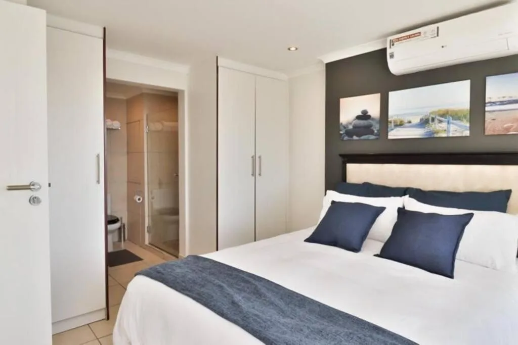 Modern bedroom with queen bed, navy pillows, and ensuite bathroom access