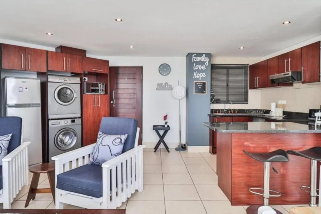 Open-plan kitchen with red cabinetry, stainless appliances, island seating, and laundry facilities