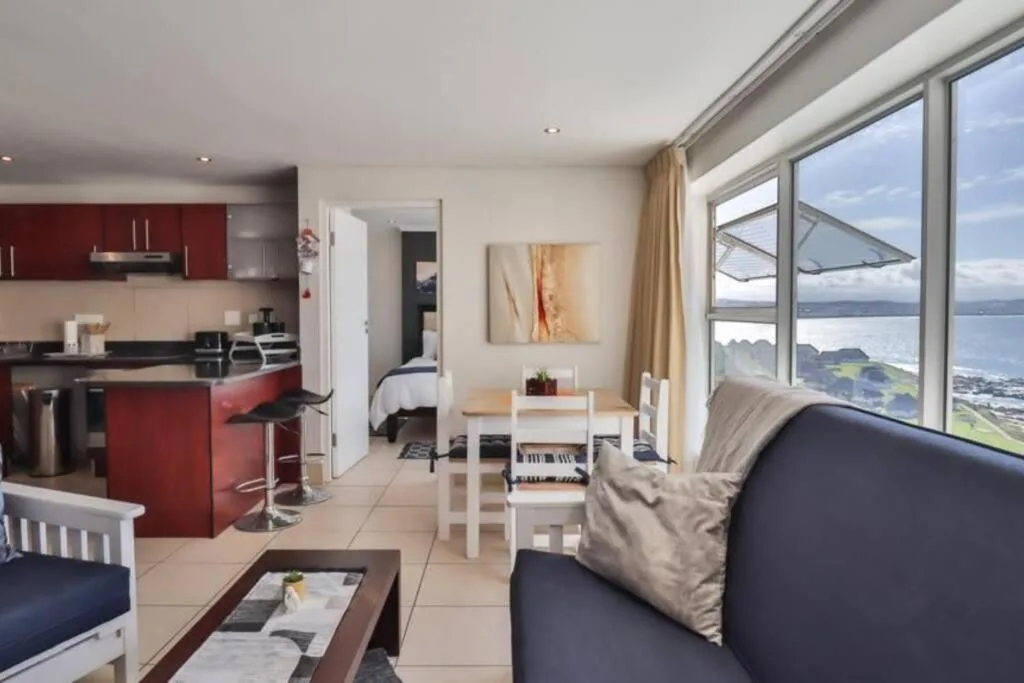 Open-plan lounge with sofa, ocean view windows, and modern furnishings
