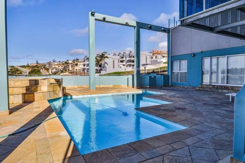Rectangular swimming pool on paved terrace with coastal town views beyond