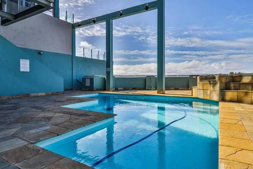 Indoor swimming pool with lane markings and large windows overlooking cloudy sky