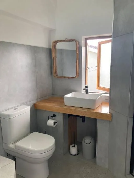 Modern bathroom with white vessel sink, wooden frame mirror, and toilet