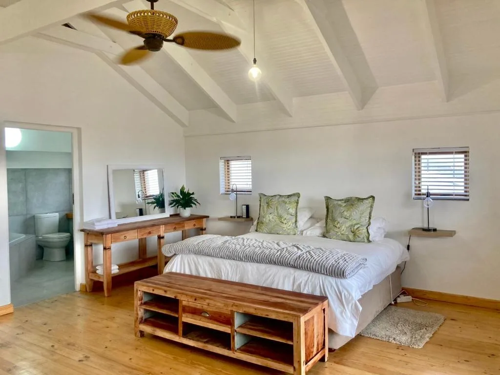 Spacious bedroom with wooden bed frame, en-suite bathroom, and ceiling fan