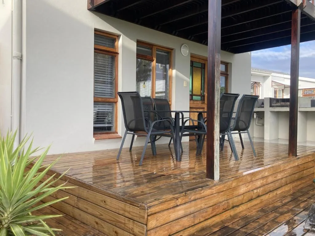 Wooden deck with black outdoor chairs and table under covered veranda