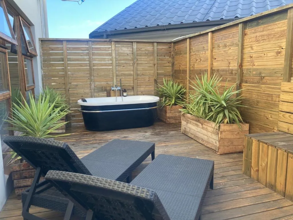 Private wooden deck with outdoor loungers, hot tub, and potted plants