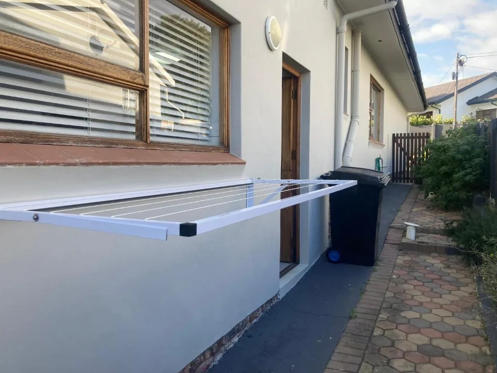 Outdoor deck area with clothesline and brick paving beside house