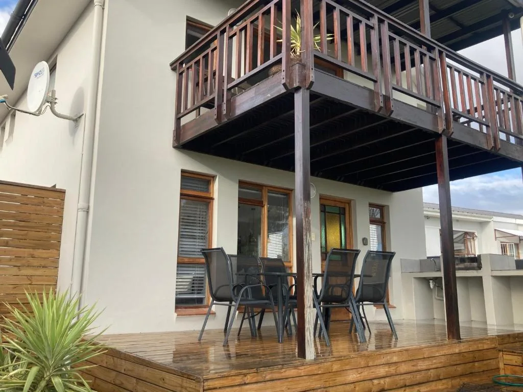 Wooden deck with dining chairs under covered upper balcony