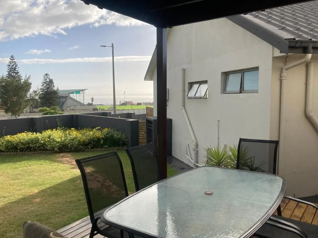 Covered patio with dining table overlooking manicured lawn and garden