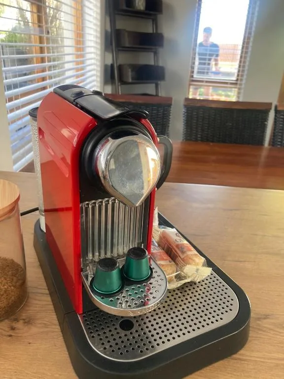 Red and black coffee machine with green capsules on wooden counter
