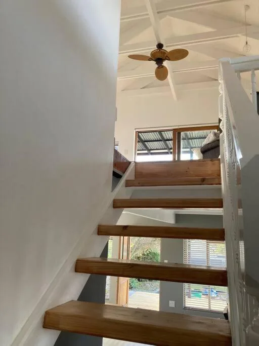 Modern wooden staircase with ceiling fan and natural light from windows