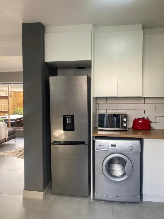 Modern kitchen with stainless steel fridge, washing machine, and white cabinetry