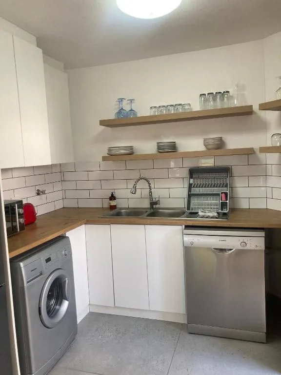 Modern kitchen with white cabinetry, wooden counters, subway tile backsplash, and stainless steel appliances
