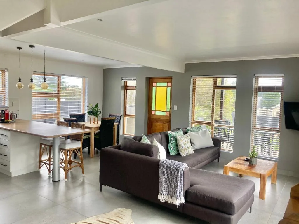 Modern lounge with dark sofa, wooden coffee table, and natural light from large windows