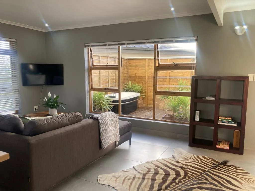 Modern living room with gray sofa, wall-mounted TV, and deck access