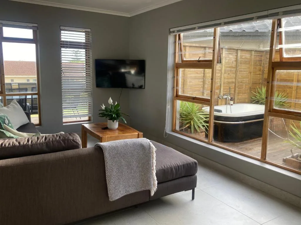 Modern lounge with gray sofa, wall-mounted TV, and large sliding doors opening to deck