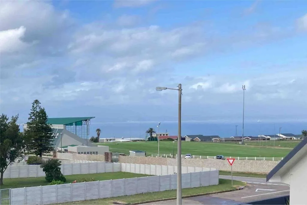 Coastal vista with ocean horizon, green fields and blue sky