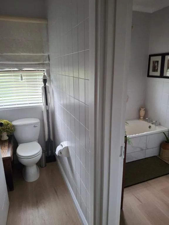 Modern bathroom with white tile walls, toilet, and vanity sink