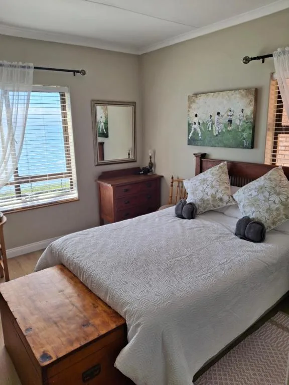 Bright bedroom with queen bed, wooden furniture, and garden view window