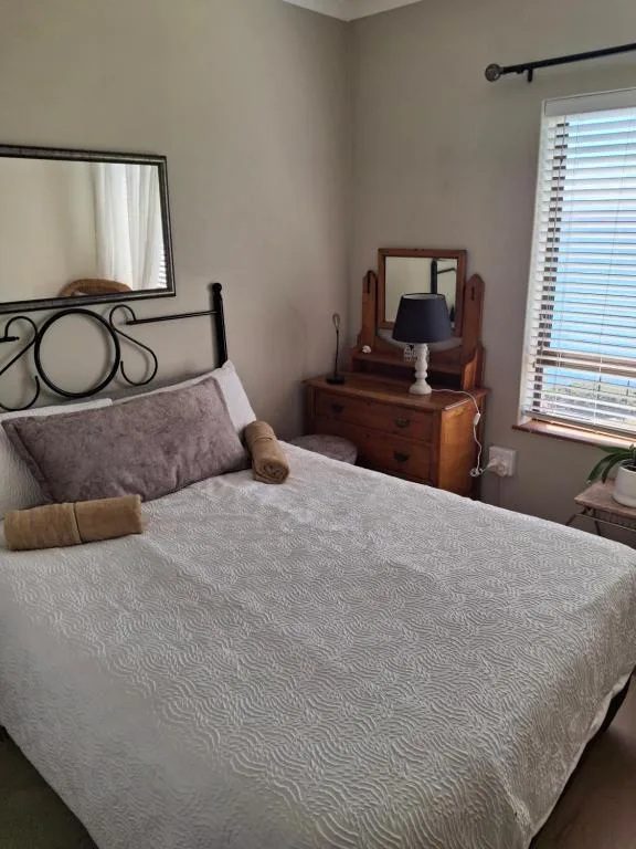 Cozy bedroom with double bed, wooden dresser, and natural light from windows