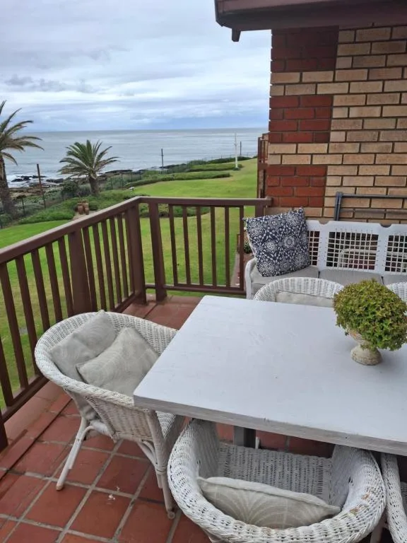Outdoor patio with wicker chairs overlooking green lawns and ocean views